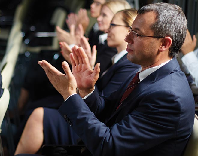 Audience members clapping during indoor event