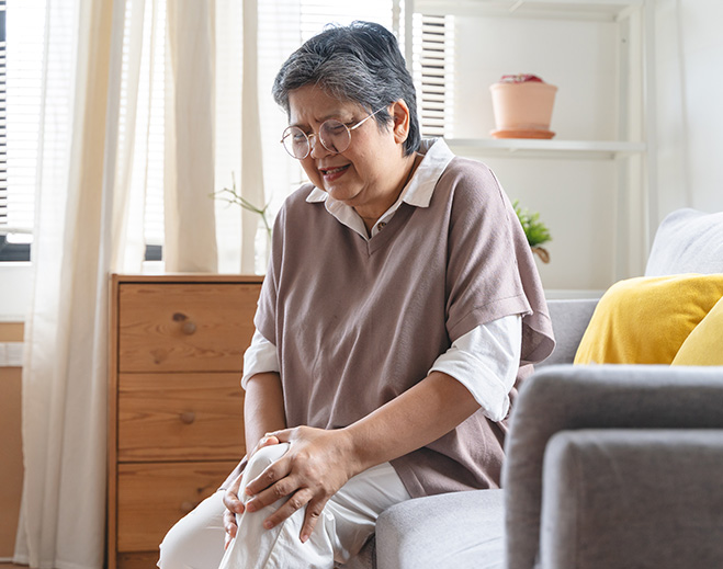 Person holding knee while sitting indoors