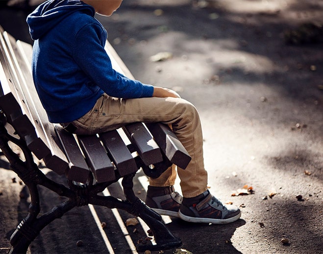 Child sitting alone on park bench
