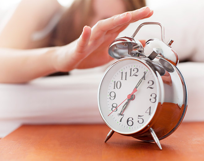 Hand reaching to turn off alarm clock