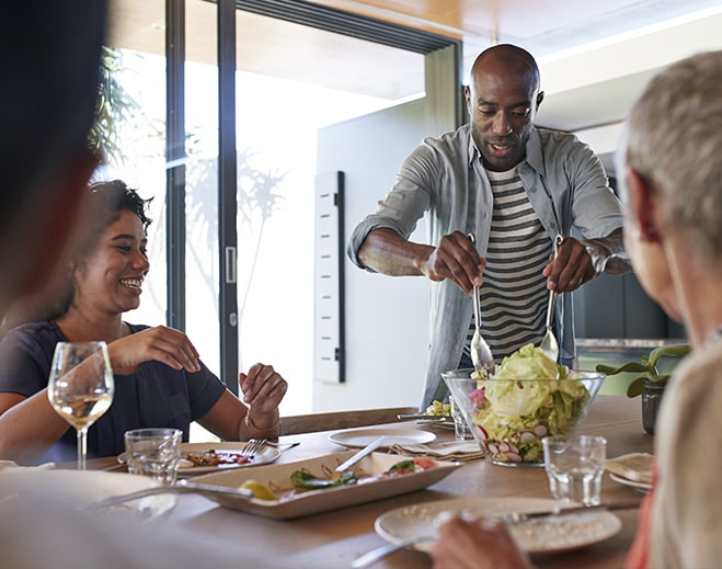 Person serving salad at dining table